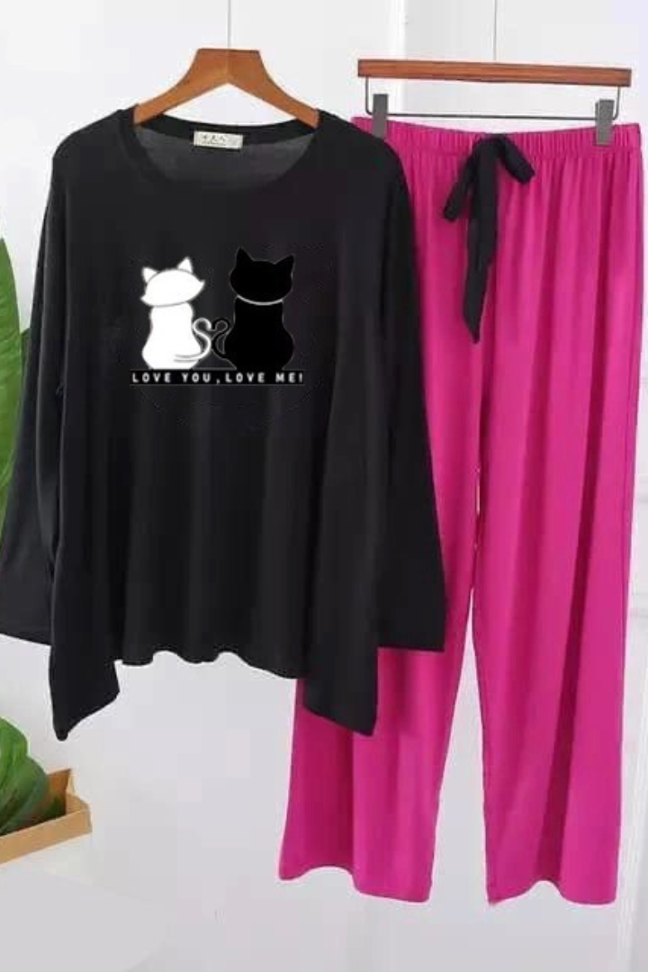 Black long-sleeve top with cat design and pink pants on a hanger against a white background.